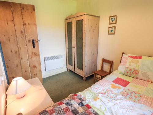 a bedroom with a bed and a cabinet and a chair at Ellis Howe in Coniston