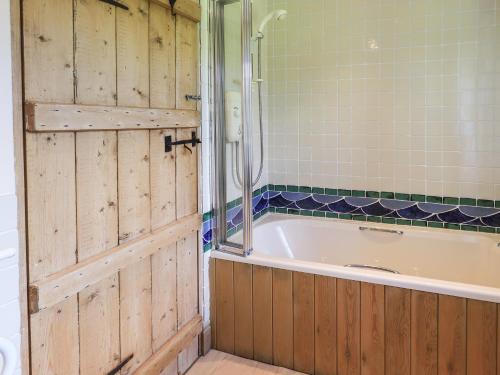 a bathroom with a tub and a shower and a door at Ellis Howe in Coniston