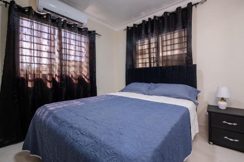 a bedroom with a blue bed and two windows at Luxury, cozy apartment Malecon / 3 min Downtown in Santo Domingo