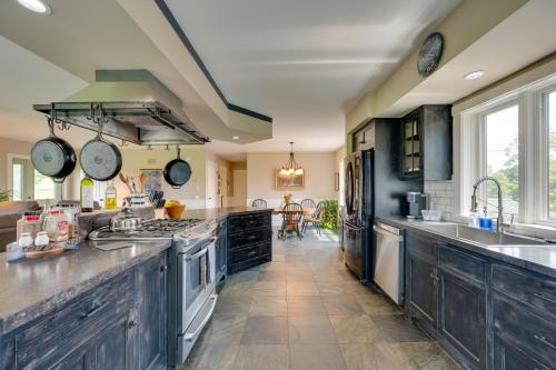 a large kitchen with black cabinets and a stove top oven at On-Site VAST Hiking Trail Hardwick Farmhouse! in Hardwick
