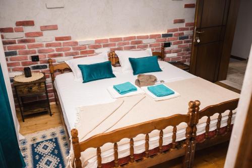 a bed with two blue pillows and a brick wall at Guest house Mirah in Ulcinj