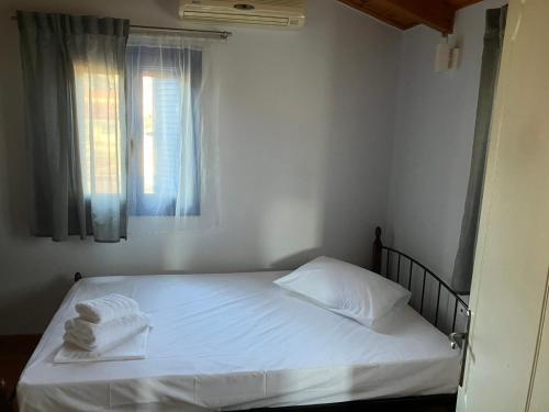 a bedroom with a bed with white sheets and a window at Nektarios House in Peratiá