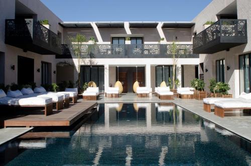 a hotel with a swimming pool with chairs and a building at Cesar Resort & Spa in Marrakech