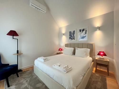 a bedroom with a white bed and a blue chair at Nomads Lux - 2BDR Almada Private Porto in Porto