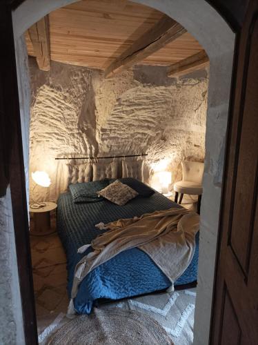 une chambre avec un lit dans un mur de pierre dans l'établissement Gite des Perreyeurs - maison troglodyte avec vue sur Loire, à Montsoreau