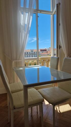 une table et des chaises en verre dans une chambre avec fenêtre dans l'établissement Apartement GT, à Nice