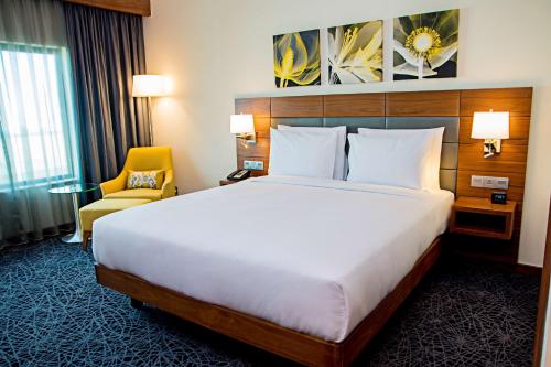 een hotelkamer met een groot bed en een stoel bij Hilton Garden Inn Nairobi Airport in Nairobi