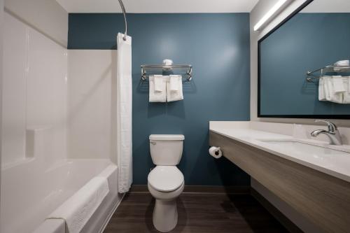 a bathroom with a toilet and a tub and a sink at WoodSpring Suites East Lansing - University Area in East Lansing