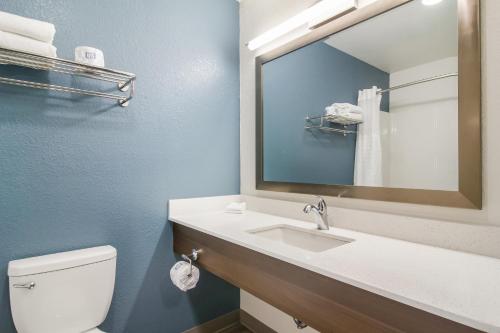 a bathroom with a toilet and a sink and a mirror at WoodSpring Suites East Lansing - University Area in East Lansing