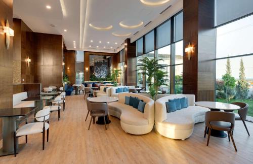 un restaurante con sofás, mesas y ventanas en Doubletree by Hilton Van, en Van