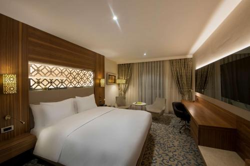 a hotel room with a large white bed and a desk at Doubletree By Hilton Elazig in Elazığ