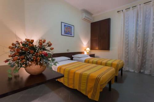 a hotel room with two beds and a vase of flowers at B&B Casa Cosmano in Brancaleone Marina