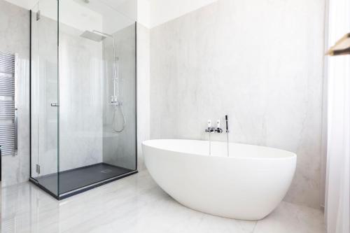 a white bathroom with a tub and a glass shower at Hôtel Restaurant le Touring - Teritoria in Saint-Raphaël