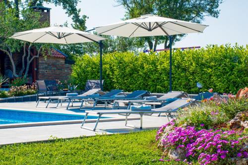 a group of chairs and umbrellas next to a pool at Villa Afrodita in Pula-Istrien in Pula
