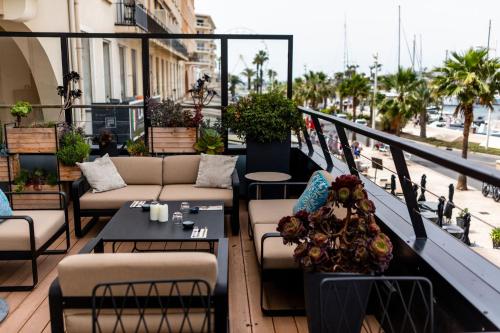 a balcony with couches and tables on a building at Hôtel Restaurant le Touring - Teritoria in Saint-Raphaël