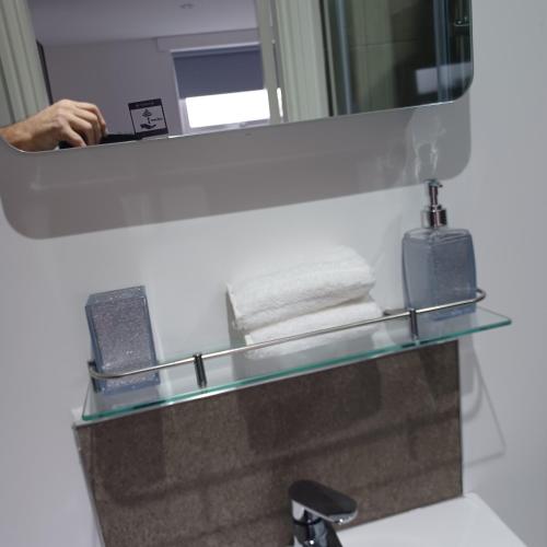 a mirror above a bathroom sink with towels on a shelf at Premier house in Whitby