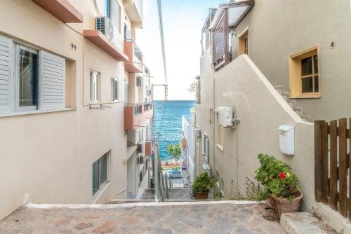 an alley between two buildings with the ocean in the background at The Holiday Choice 1 in Agios Nikolaos