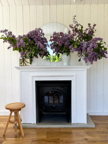 a fireplace with two vases of purple flowers on it at Ragnar Glamp Pitrags Lux in Pitragutsiyeme