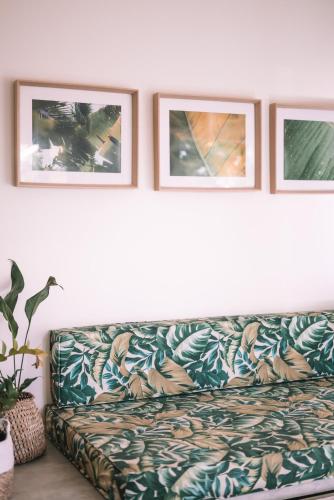 a couch in a living room with three pictures on the wall at Cactus Lodge Pipa in Pipa