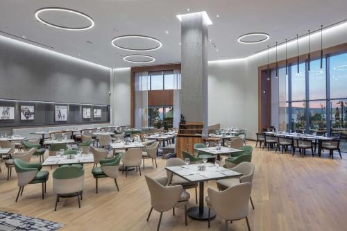 a restaurant with tables and chairs and windows at Doubletree By Hilton Canakkale in Canakkale