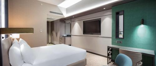 a bedroom with a white bed and a flat screen tv at Doubletree By Hilton Canakkale in Canakkale