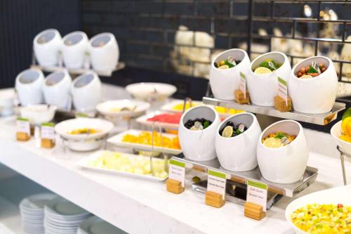 a buffet of food in white bowls on a table at DoubleTree By Hilton Izmir Airport in Izmir