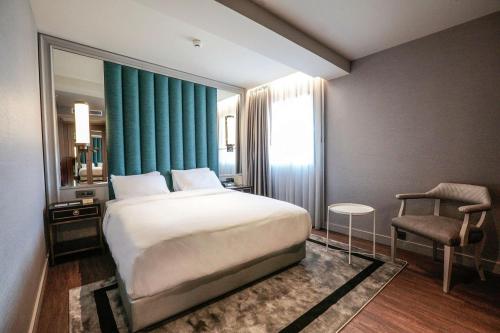 a bedroom with a large bed and a chair at DoubleTree By Hilton Izmir Airport in Izmir