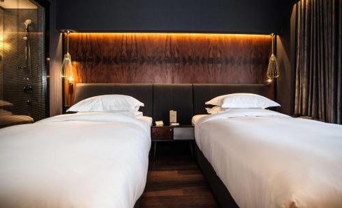 two beds in a hotel room with white sheets at DoubleTree By Hilton Izmir Airport in Izmir