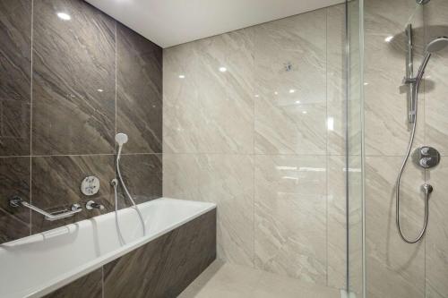 a bathroom with a shower and a bath tub at Doubletree By Hilton Antalya City Centre in Antalya