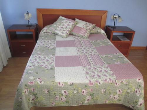 a bed with a pink and green quilt on it at Hotel Brisas del Sella in Ribadesella