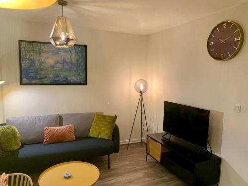 a living room with a couch and a clock on the wall at Rode Bosuil: thuiskomen op De Veluwe! in Otterlo