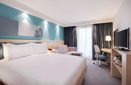 a hotel room with a white bed and a tv at Hampton By Hilton Bristol Airport in Redhill