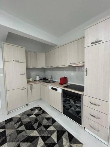 a kitchen with white cabinets and a black and white floor at Cozy Corner Apartment in Gjakove
