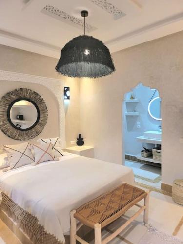 sypialnia z dużym białym łóżkiem i lustrem w obiekcie Riad Isahiac avec piscine en exclusivité w Marakeszu
