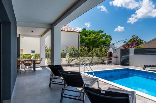 a patio with chairs and a swimming pool at House with pool Villa Angelo Vrsi in Vrsi