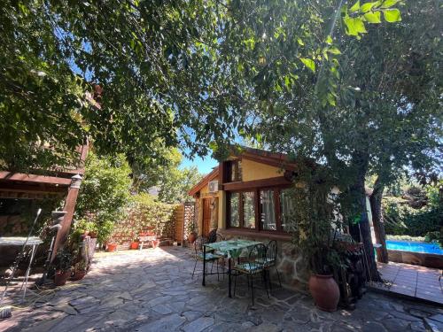 un patio de una casa con mesa y sillas en Acogedora casa rural en la sierra de Madrid en Mataelpino