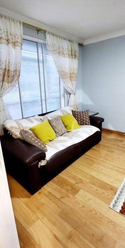 un divano con cuscini gialli in soggiorno di Holiday Apartment a Abbey Wood