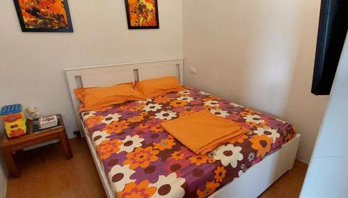 a bed with a floral comforter and two pillows on it at Cosy and roomy 78m2(Μονοκατοικία) in Piraeus
