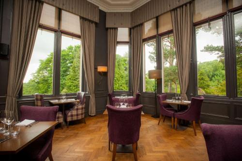 a restaurant with tables and chairs and large windows at DoubleTree by Hilton Dunblane Hydro Hotel in Dunblane