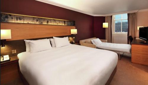 a hotel room with a large bed and a television at DoubleTree by Hilton Dunblane Hydro Hotel in Dunblane