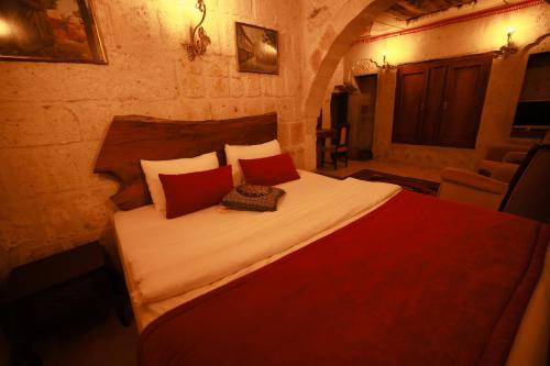 a bedroom with a large bed with red pillows at Cappadocia Nar Cave House & Swimming Pool in Nevsehir
