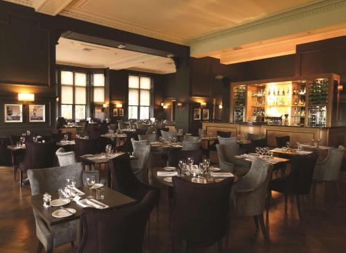 a restaurant with tables and chairs and a bar at DoubleTree by Hilton Dunblane Hydro Hotel in Dunblane