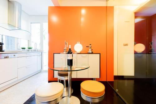 a kitchen with orange walls and a glass table and stools at Frente al parque, en el centro in Bilbao