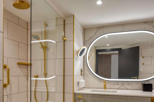 uma casa de banho com um chuveiro e um espelho. em Hilton Glasgow em Glasgow