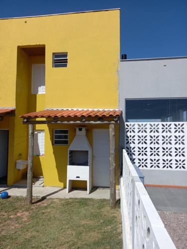 un edificio amarillo con una puerta blanca y una valla en Recanto das Pedras - Casa Pedra Ferrugem Com vista para o mar, en Jaguaruna