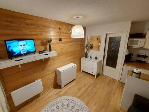 uma sala de estar com uma televisão de ecrã plano numa parede de madeira em Joli studio 4 couchages aux pieds des pistes em Puy-Saint-Vincent