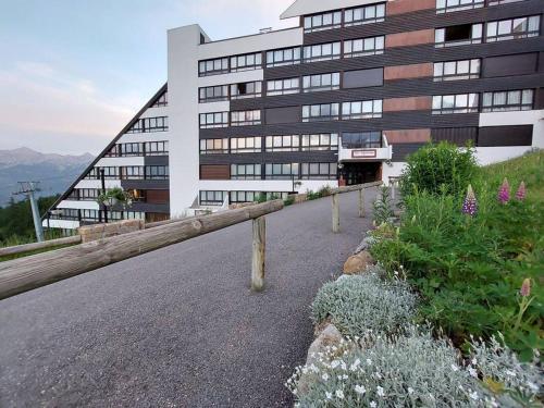 a building on a hill with flowers in front of it at Joli studio 4 couchages aux pieds des pistes in Puy-Saint-Vincent
