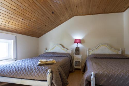 two beds in a bedroom with a wooden ceiling at Casas do Patrao II in Sabugueiro