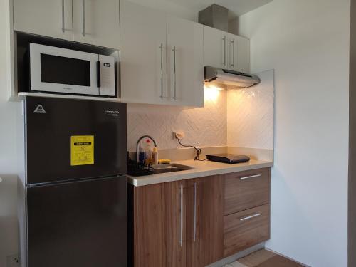 a kitchen with a black refrigerator and a microwave at The Zen Suites at Matina Enclaves in Davao City