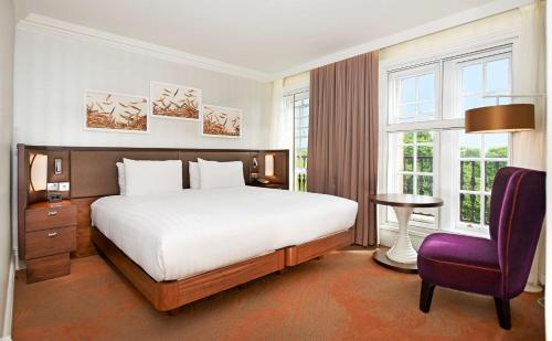 a bedroom with a large bed and a purple chair at Hilton London Hyde Park in London